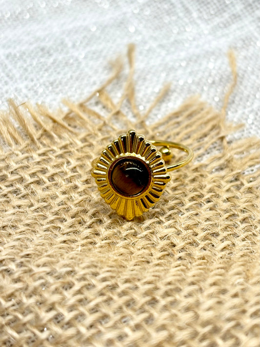 Bague ALYSÉE, de couleur dorée avec pierre d'Oeil de Tigre, exposée sur un fond en lin et toile de jute.