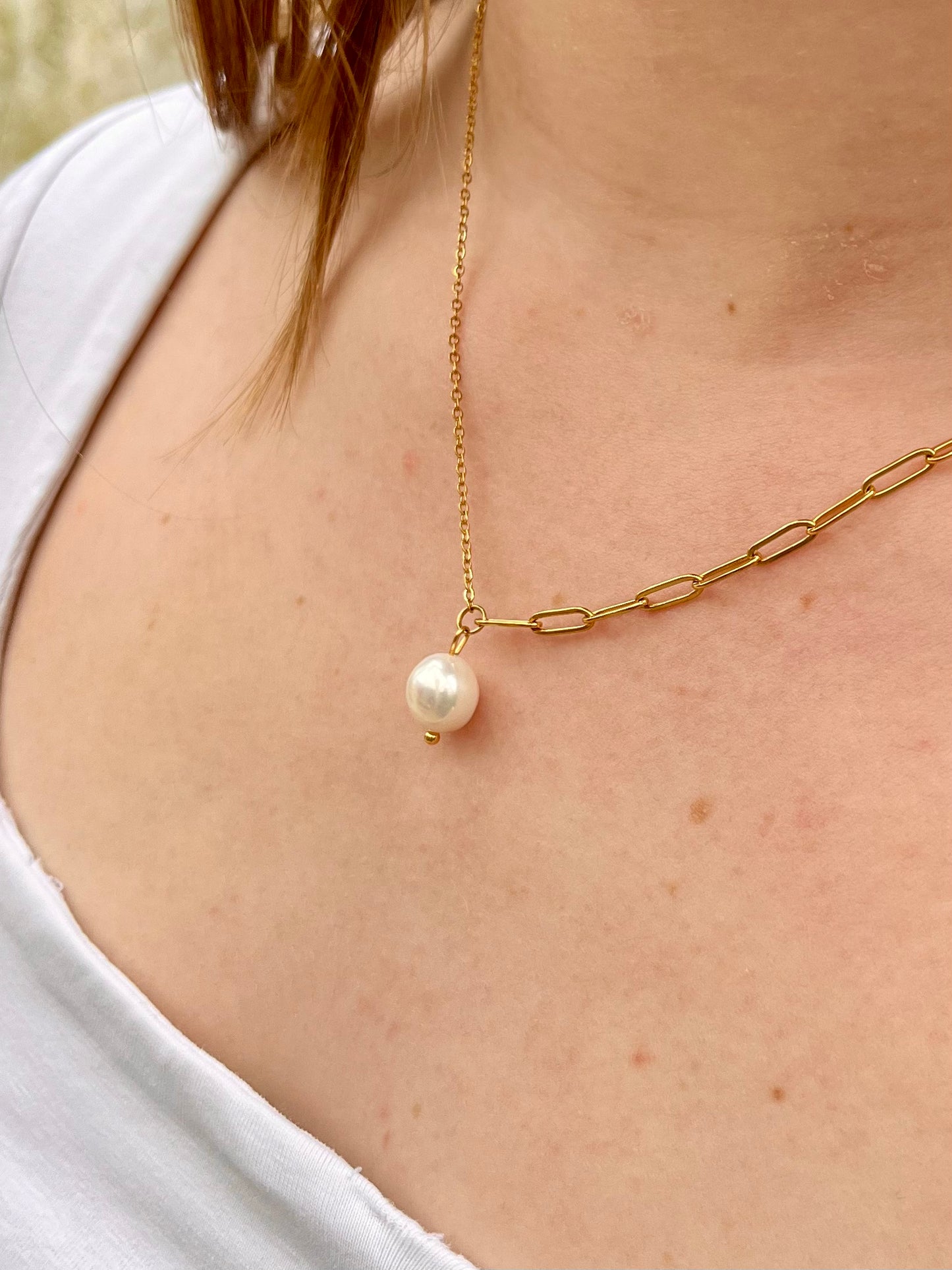 Collier ANGÈLE, de couleur dorée avec Perle de Culture, porté sur un haut blanc.