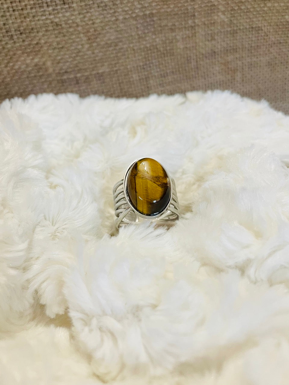 Bague DIANA, avec pierre d'Oeil de Tigre, exposée sur un fond en fourrure.