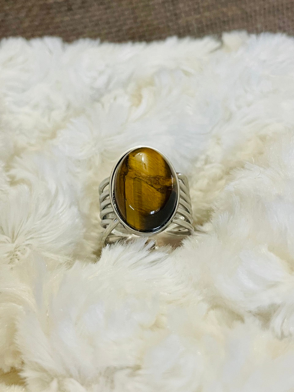 Bague DIANA, avec pierre d'Oeil de Tigre, exposée sur un fond en fourrure.