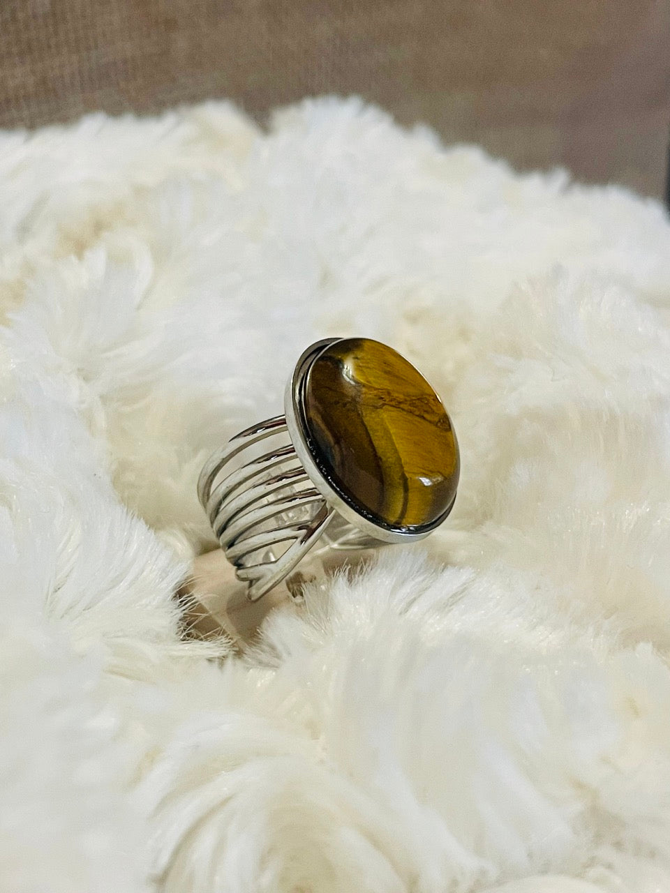 Bague DIANA, avec pierre d'Oeil de Tigre, exposée sur un fond en fourrure.