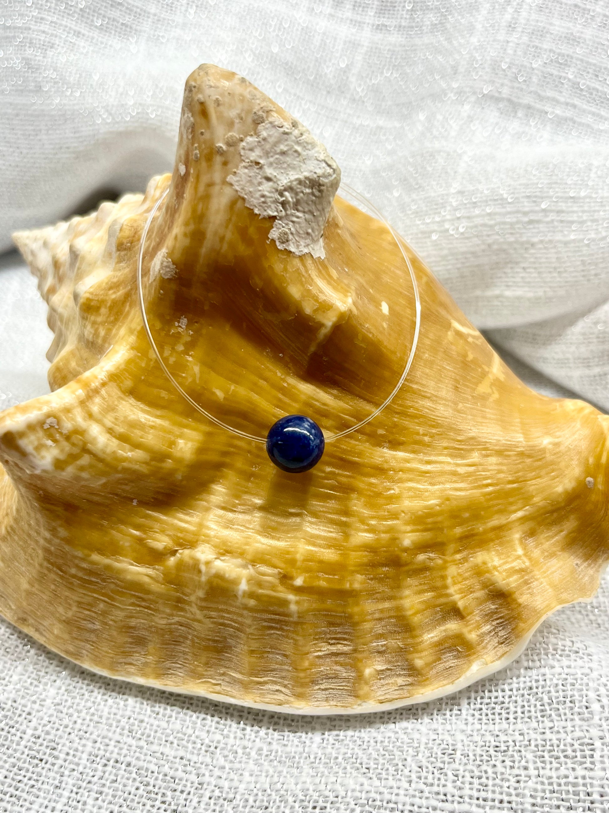 Collier EMY avec pierre de Sodalite, exposé sur un coquillage.