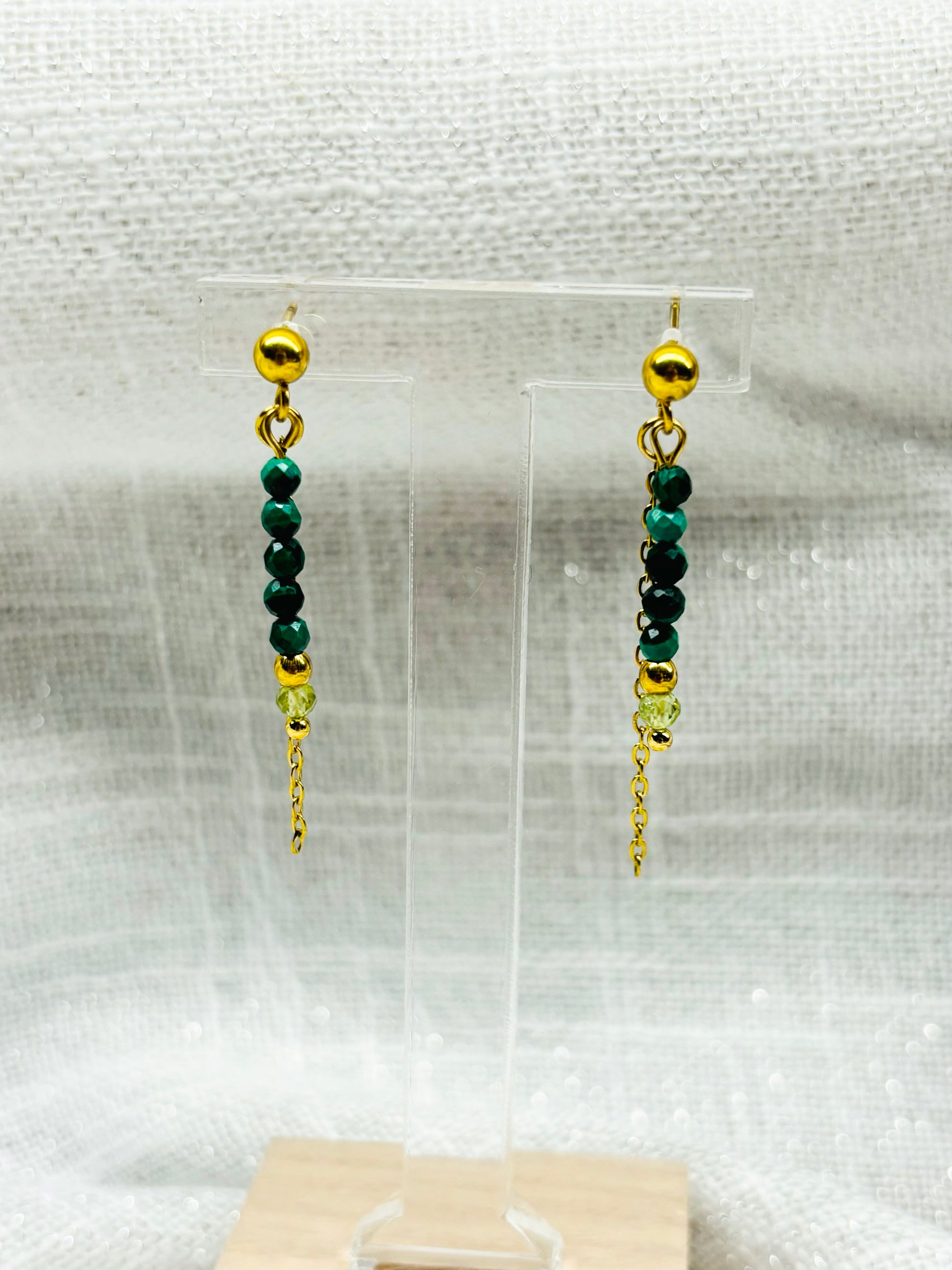 Boucles d'oreille JULIETTE, avec pierres de Malachite et de Péridot, exposées sur un fond en lin.