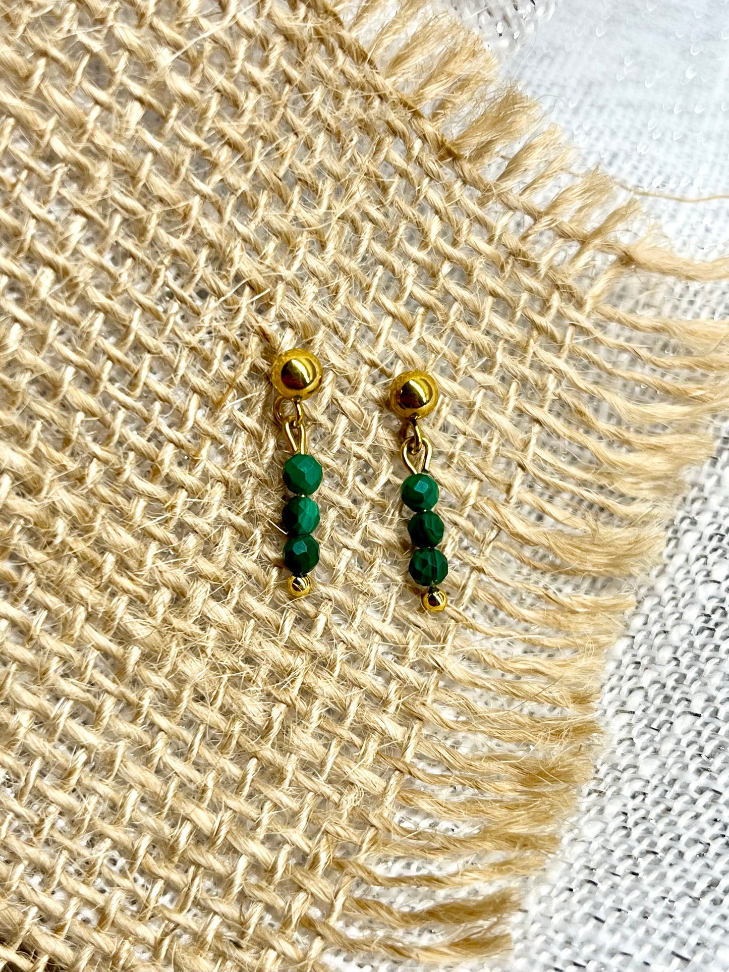 Boucles d'oreille LALY, avec pierres de Malachite, exposées sur un fond en toile de jute.