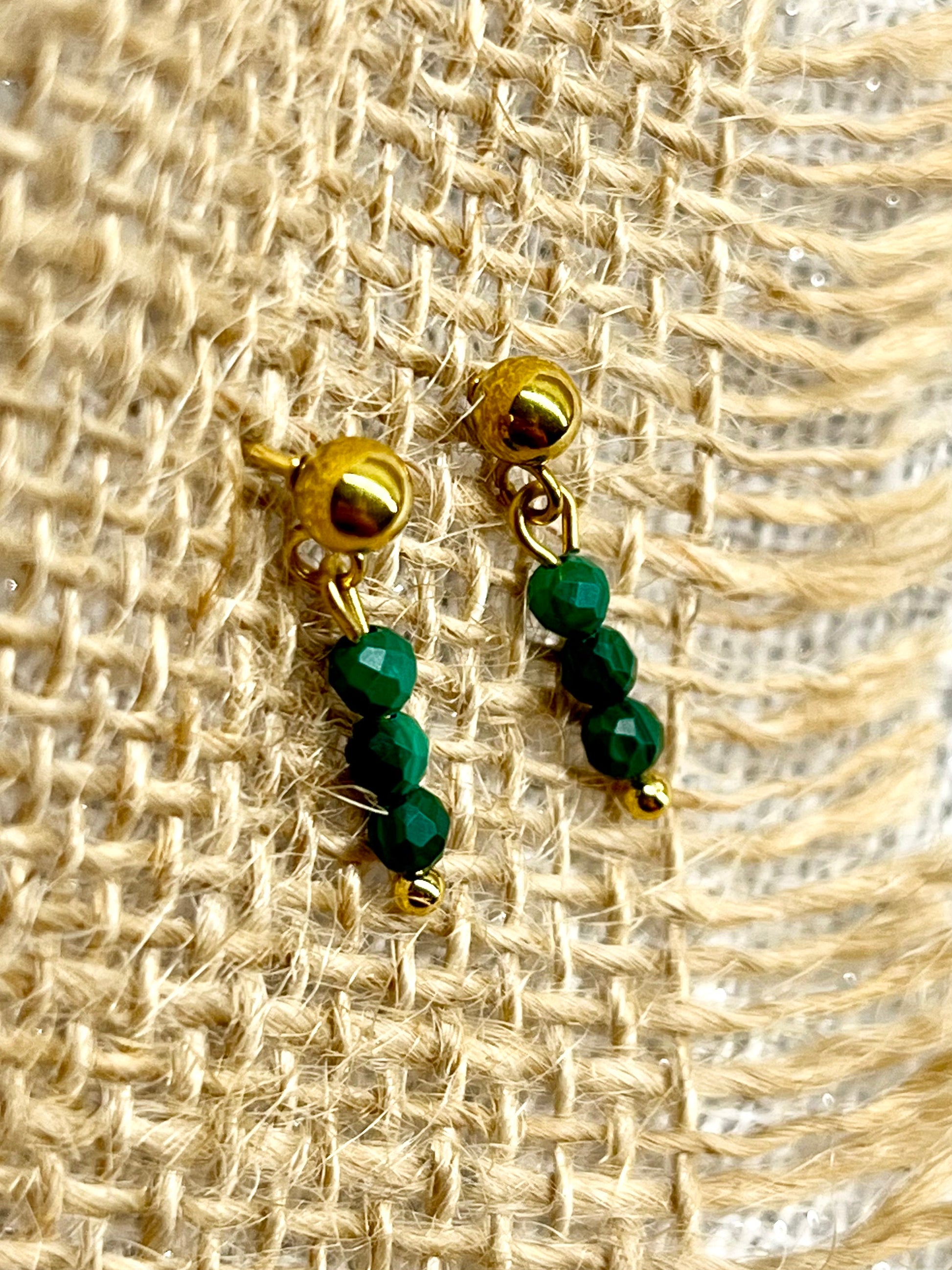 Boucles d'oreille LALY, avec pierres de Malachite, exposées sur un fond en toile de jute.