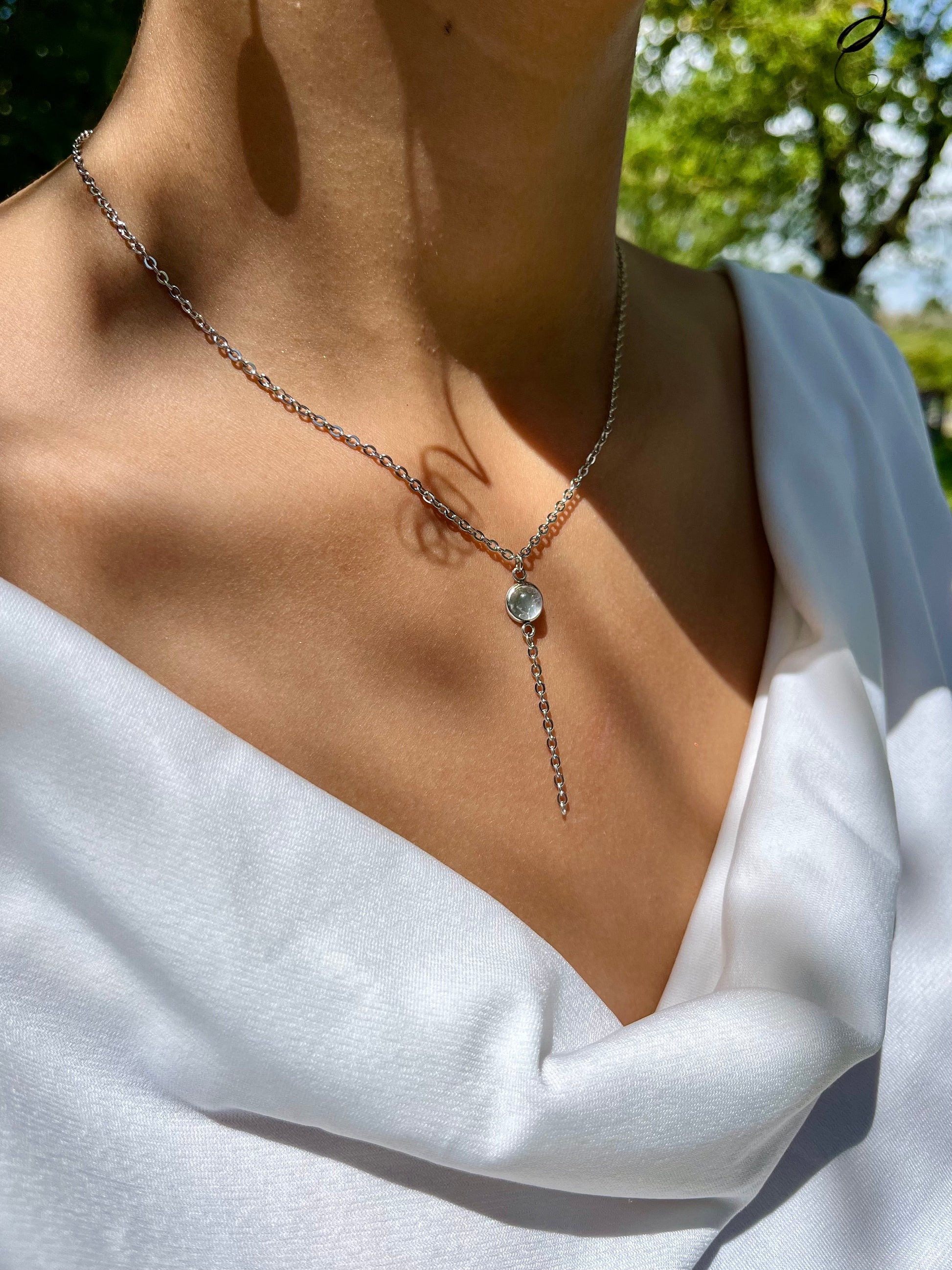 Collier LÉA, en acier inoxydable argent et pierre de Quartz Rose, porté par une femme sur un haut blanc.