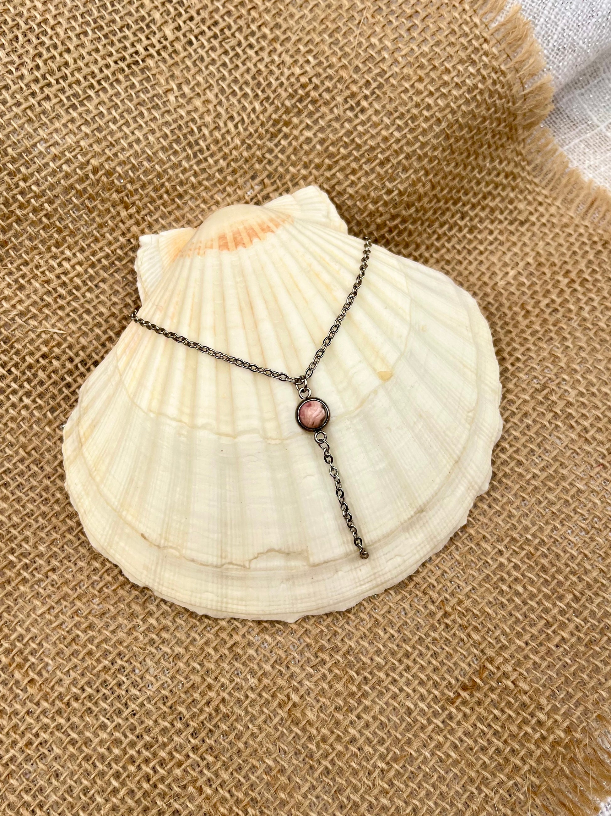 Collier LÉA, avec pierre de Rhodochrosite, exposé sur un coquillage.