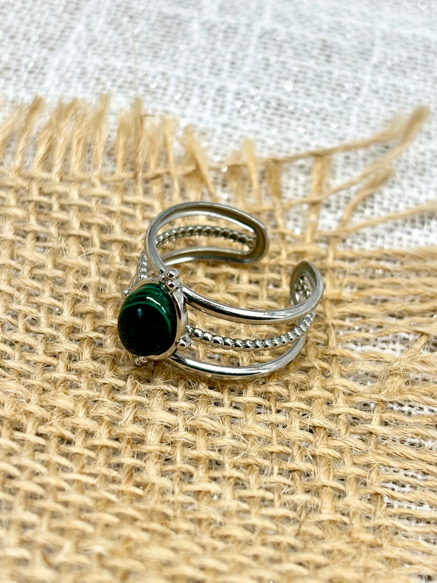 Bague LOUISON, avec pierre de Malachite, exposée sur de la toile de jute.