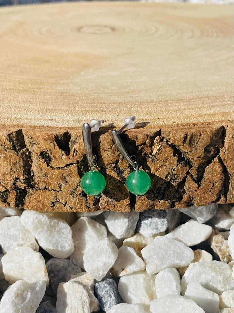 Boucles d'oreille MADELEINE, avec pierre d'Aventurine, exposées sur un rondin de bois.