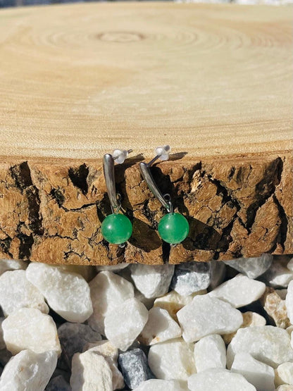 Boucles d'oreille MADELEINE, avec pierre d'Aventurine, exposées sur un rondin de bois.