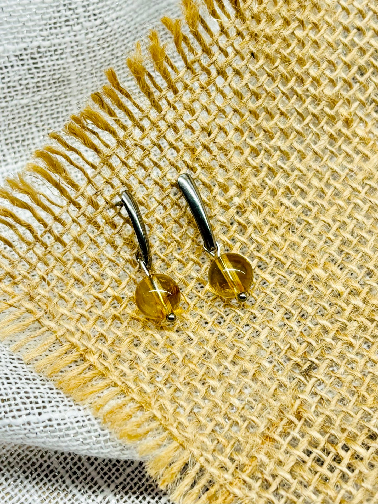 Boucles d'oreille MADELEINE, avec pierre de Citrine, exposées sur de la toile de jute..