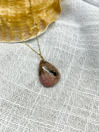 Collier MAELA, avec pierre de Rhodonite, exposé sur un fond en lin.