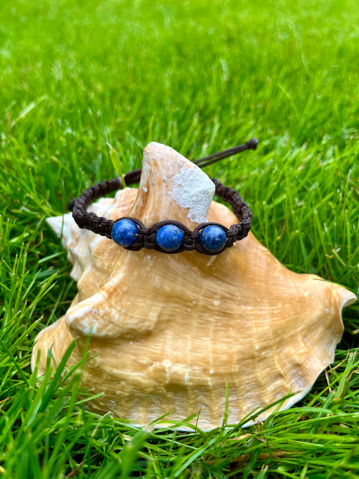 Bracelet MAËL, avec pierres de Sodalite, exposé sur un coquillage.