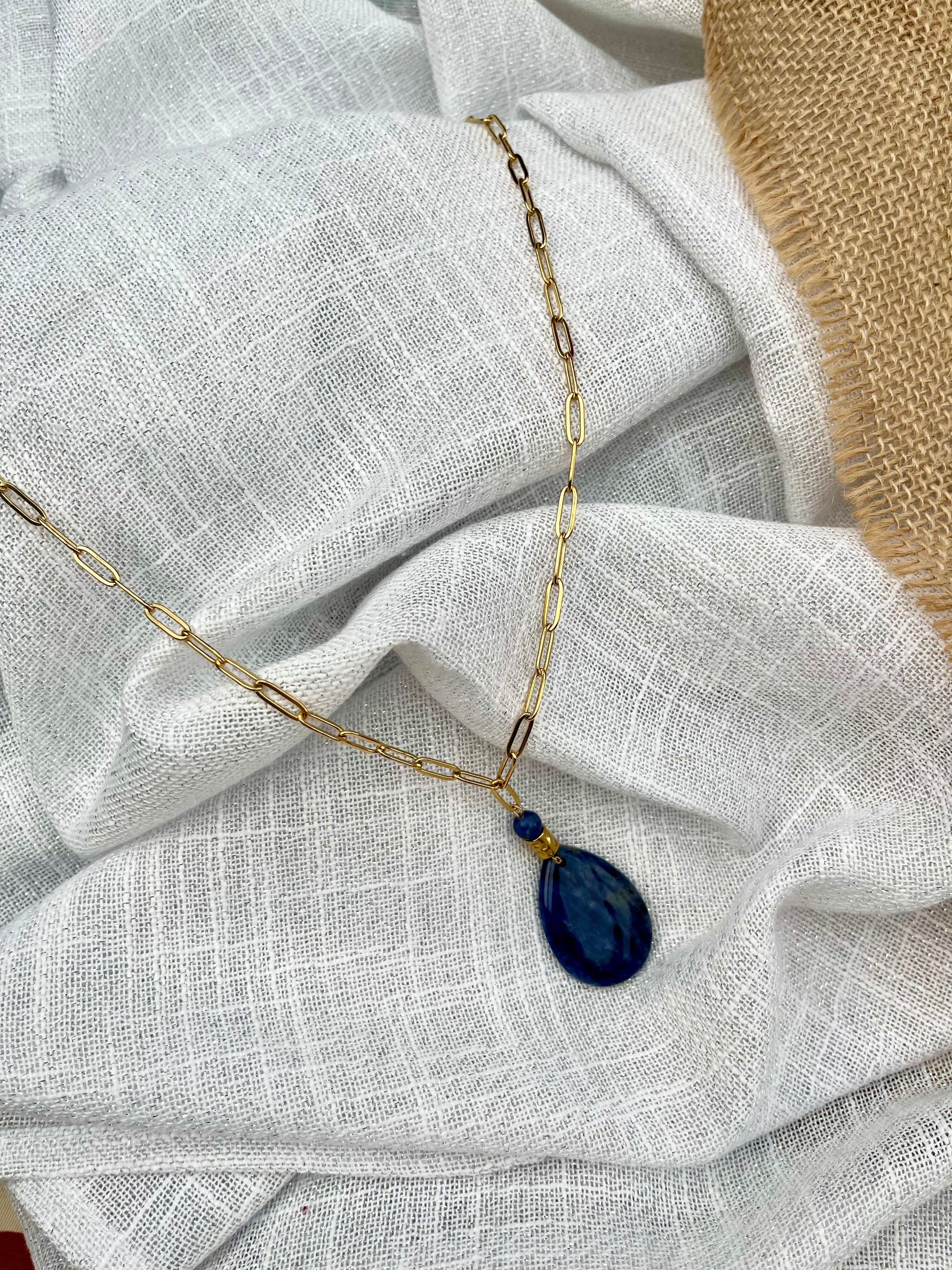 Collier MAËVA, avec pierre de Sodalite, exposé sur un fond en lin.