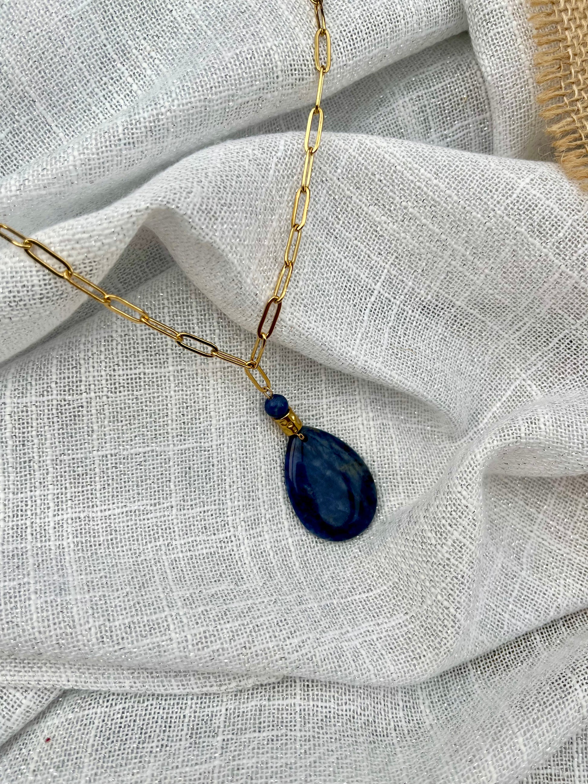 Collier MAËVA, avec pierre de Sodalite, exposé sur un fond en lin.