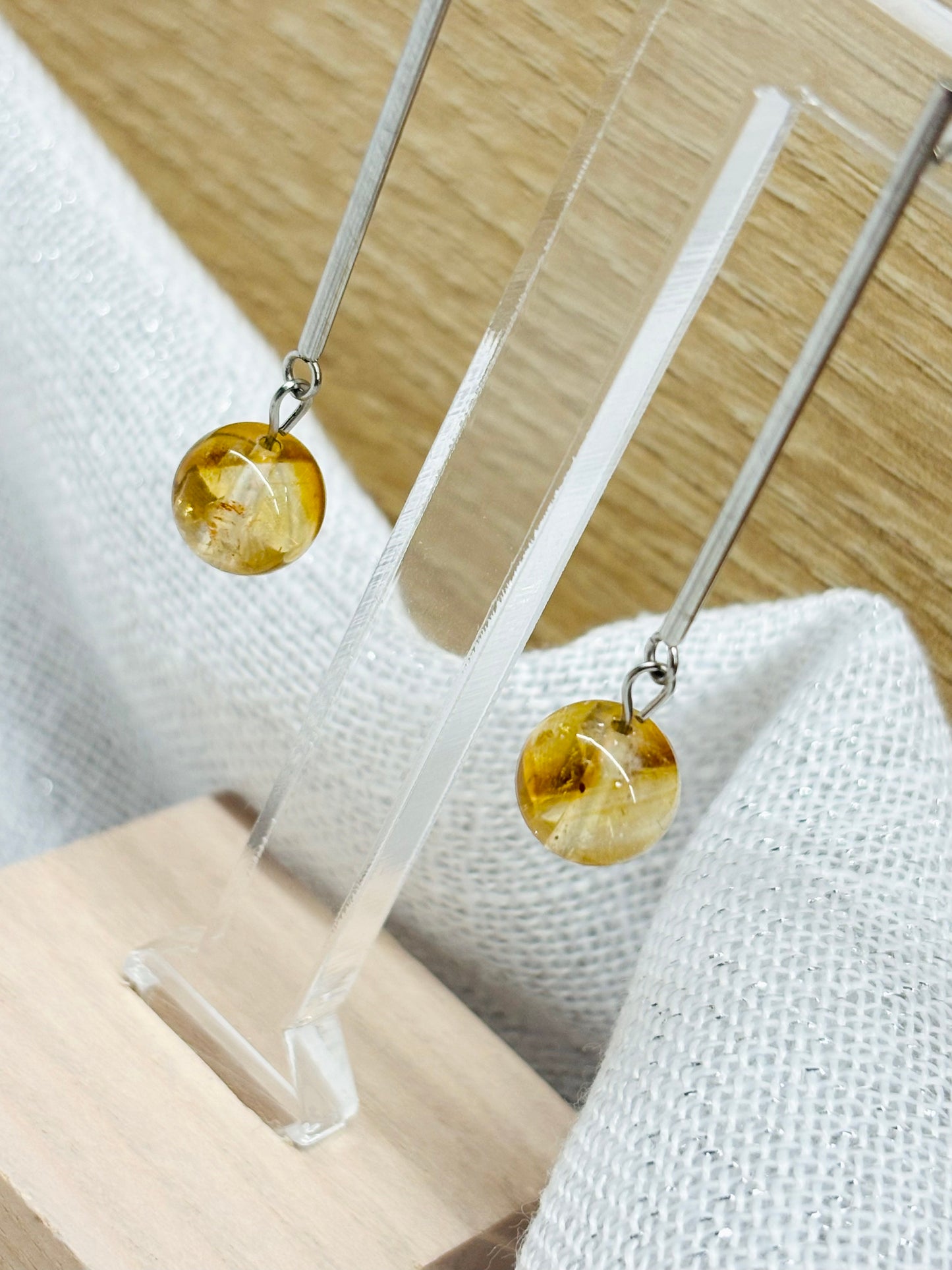 Boucles d'oreille MANON, en pierre de Citrine, exposées sur un fond en lin et en bois.