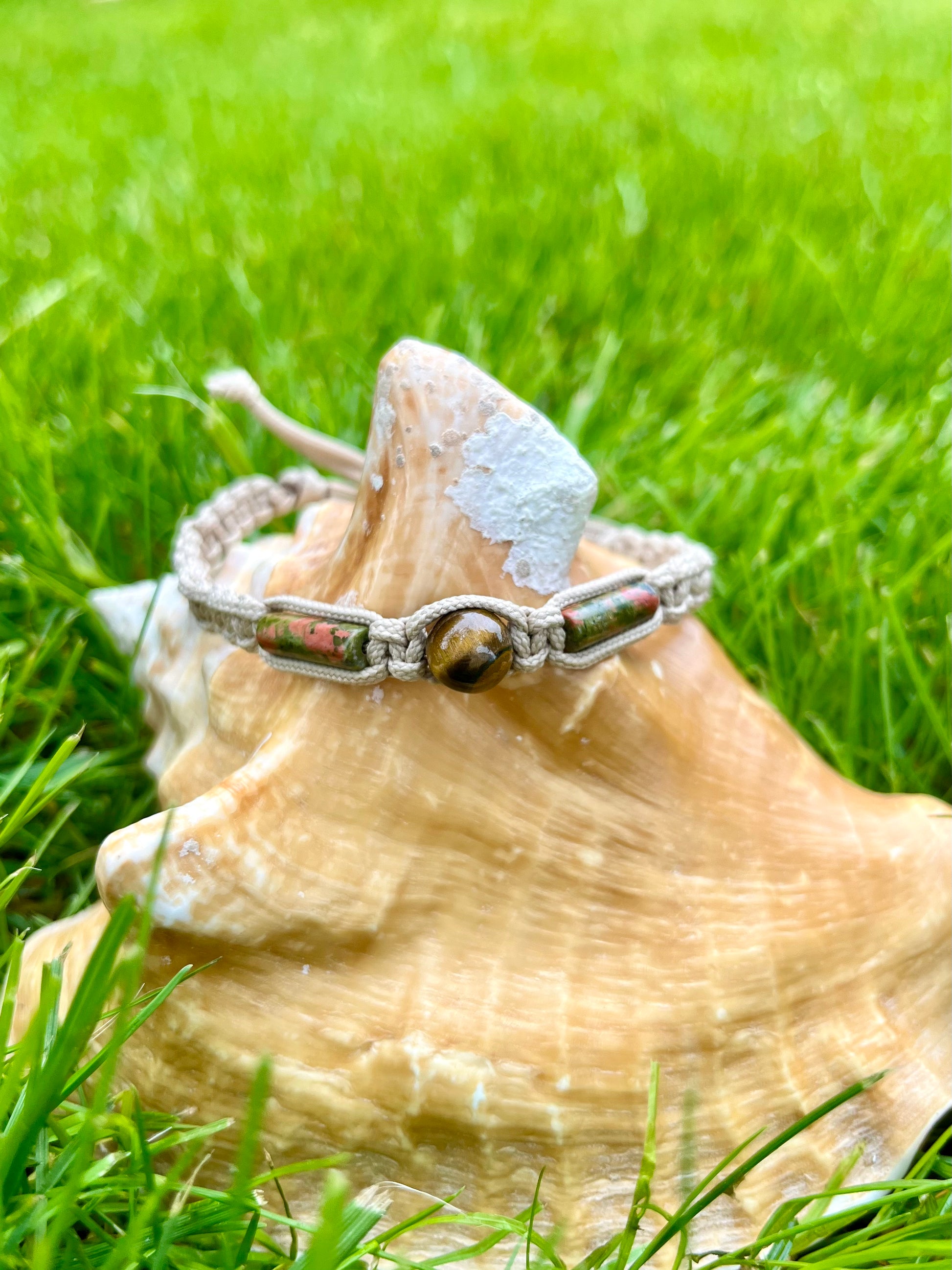 Bracelet NOAH, avec pierres d'Oeil de Tigre et d'Unakite, exposé sur un coquillage.