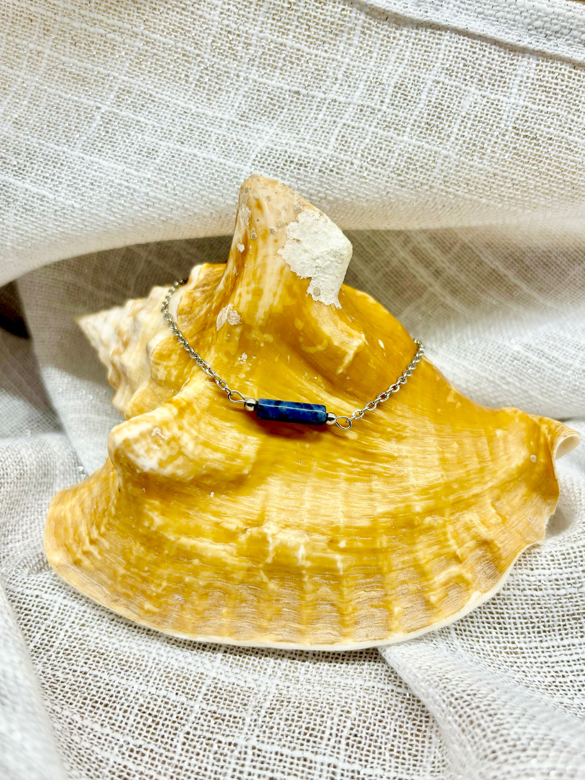 Bracelet NORA, avec pierre de Sodalite,  exposé sur un coquillage.