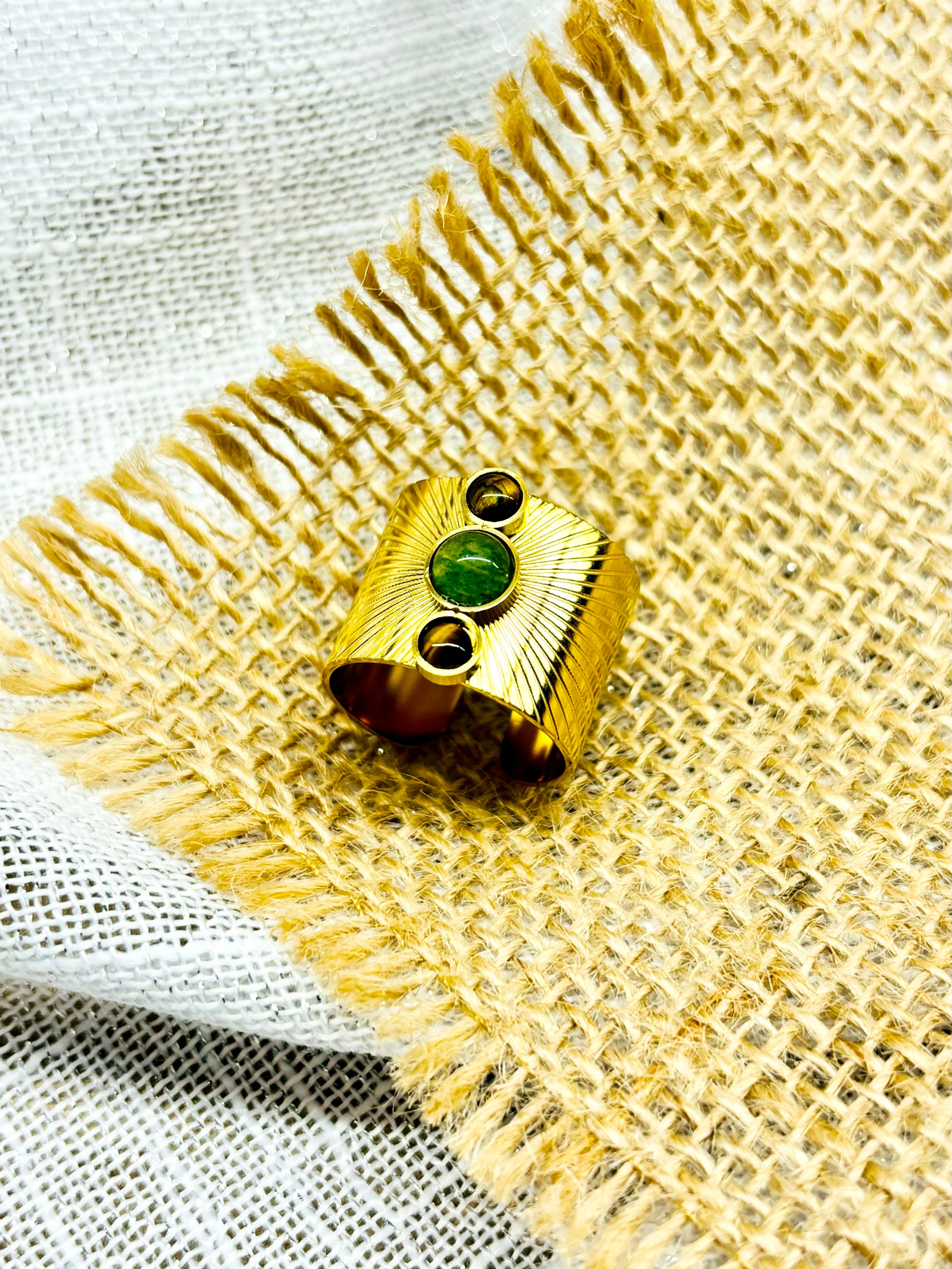 Bague SANDRA, avec pierres d'Aventurine et d'oeil de Tigre, exposée sur un fond en lin.