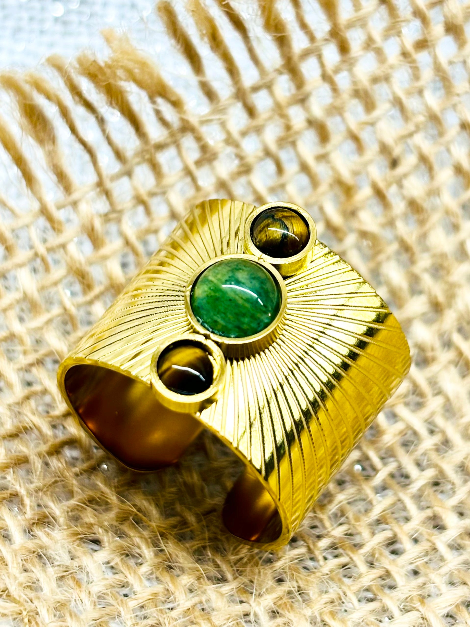 Bague SANDRA, avec pierres d'Aventurine et d'oeil de Tigre, exposée sur un fond en lin.