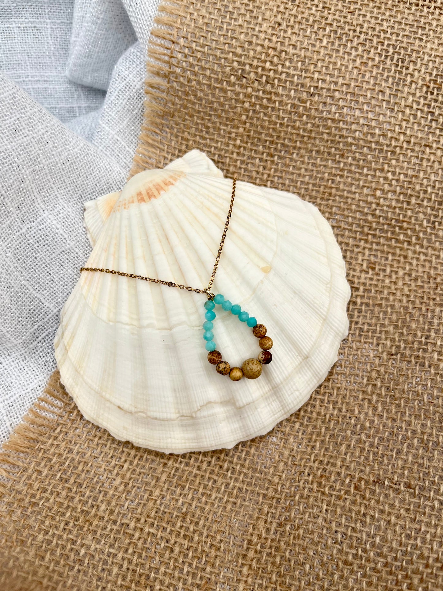 Collier SIMONA, avec pierres de Jaspe Paysage et Amazonite, exposé sur un coquillage.