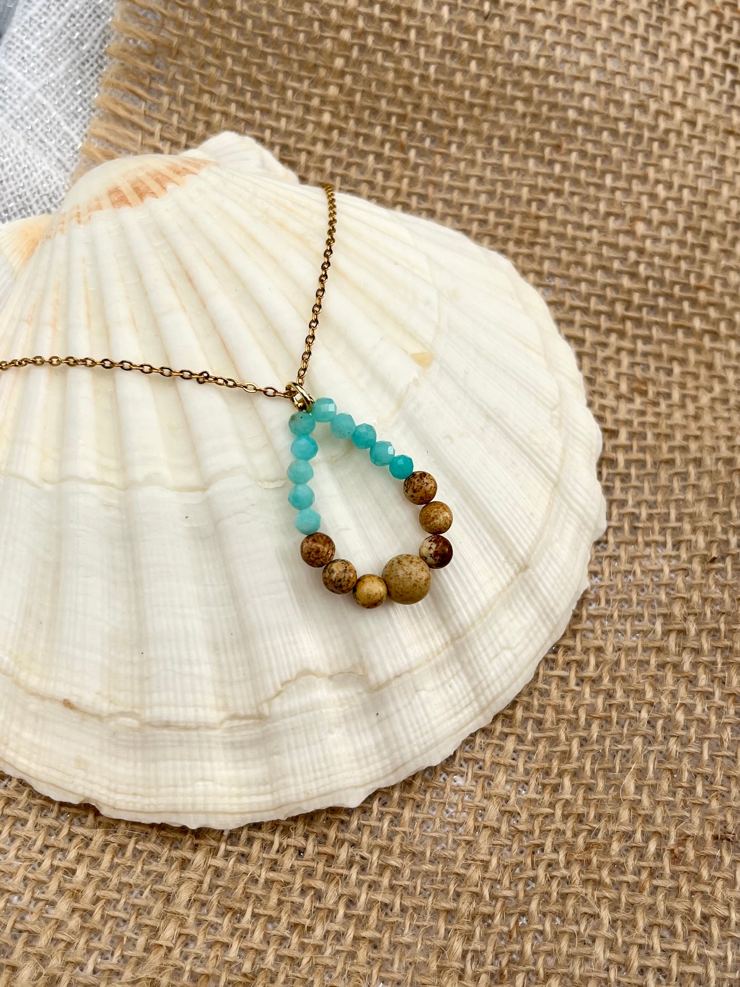 Collier SIMONA, avec pierres de Jaspe Paysage et Amazonite, exposé sur un coquillage.