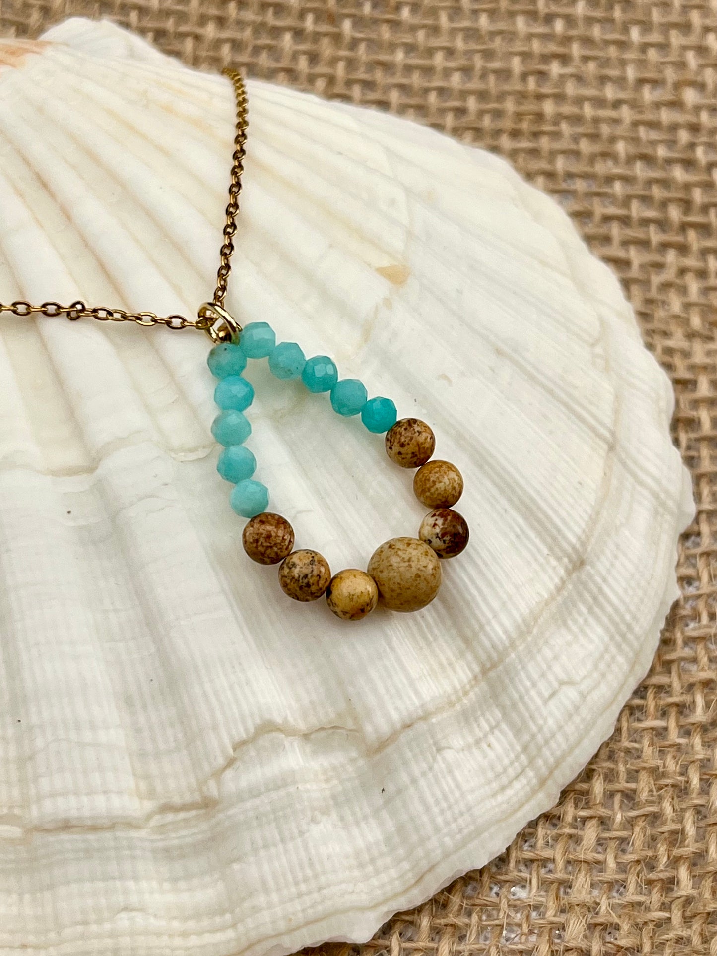 Collier SIMONA, avec pierres de Jaspe Paysage et Amazonite, exposé sur un coquillage.