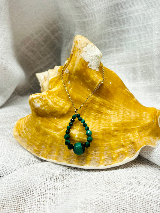 Collier SIMONA, avec pierres de Malachite, exposé sur un coquillage.