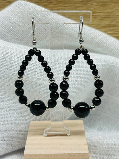 Boucles d'oreille SIMONE, avec pierres de Tourmaline Noire, exposées sur un fond en lin.