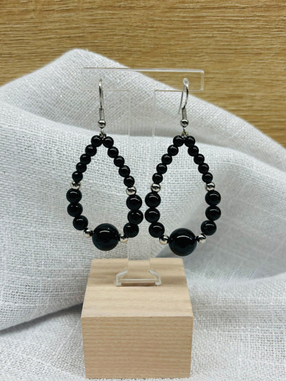 Boucles d'oreille SIMONE, avec pierres de Tourmaline Noire, exposées sur un fond en lin.