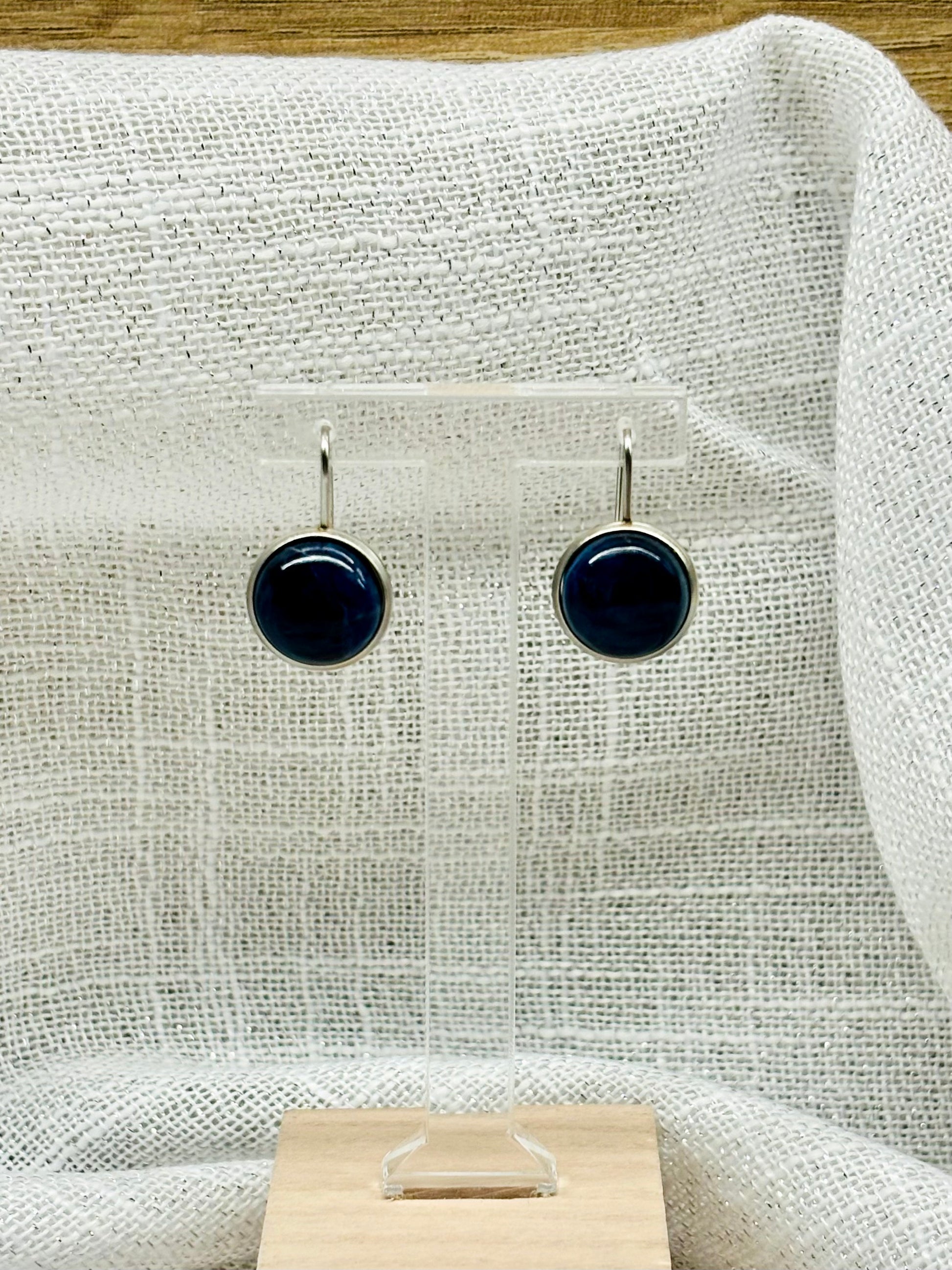 Boucles d'oreille THÉANA, avec pierre de Sodalite, exposées sur un fond en lin.