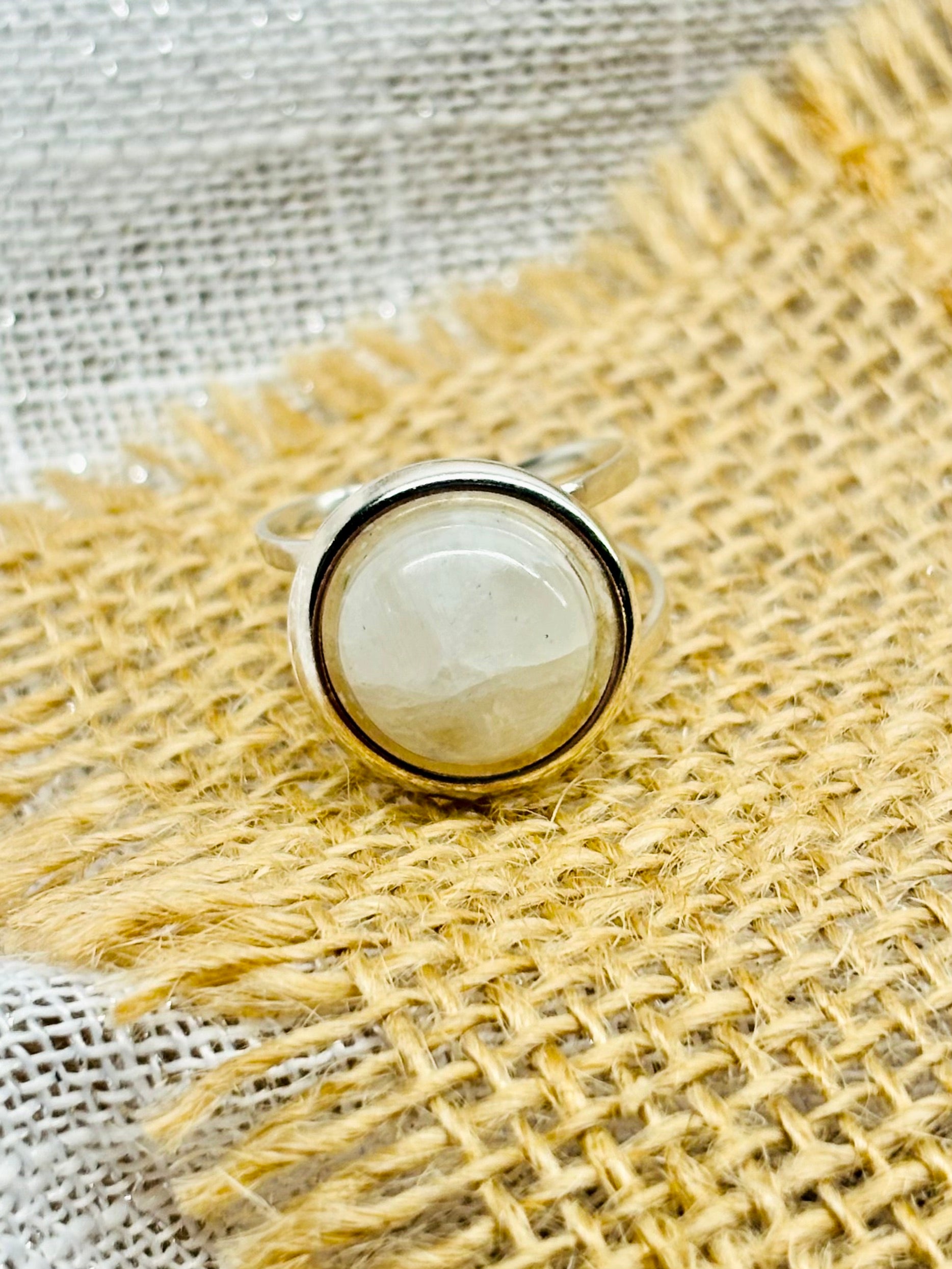 Bague THÉA, en argent et pierre de Lune, sur un fond en lin et toile de jute.