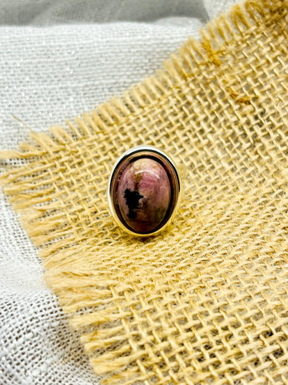 Bague THÉA, en argent et pierre de Rhodonite, sur un fond en lin et toile de jute.