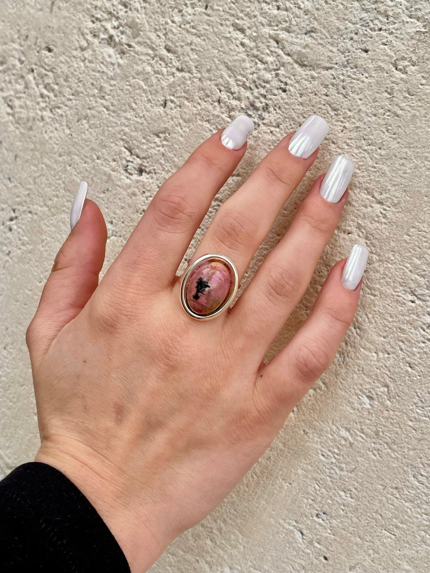 Bague THÉA, en argent et pierre de Rhodonite, portée sur une main de femme.