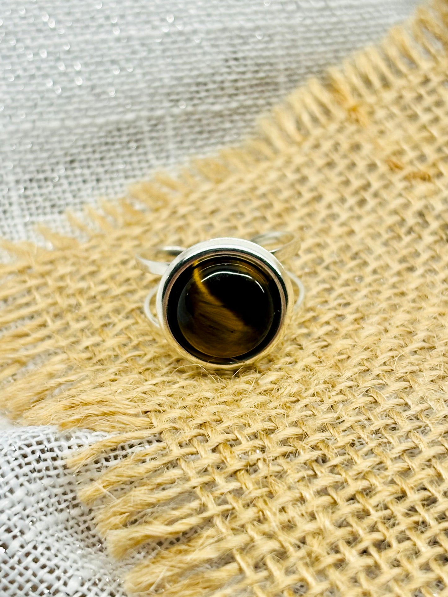 Bague THÉA, en argent et pierre d'Oeil de Tigre, sur un fond de toile de jute et lin.