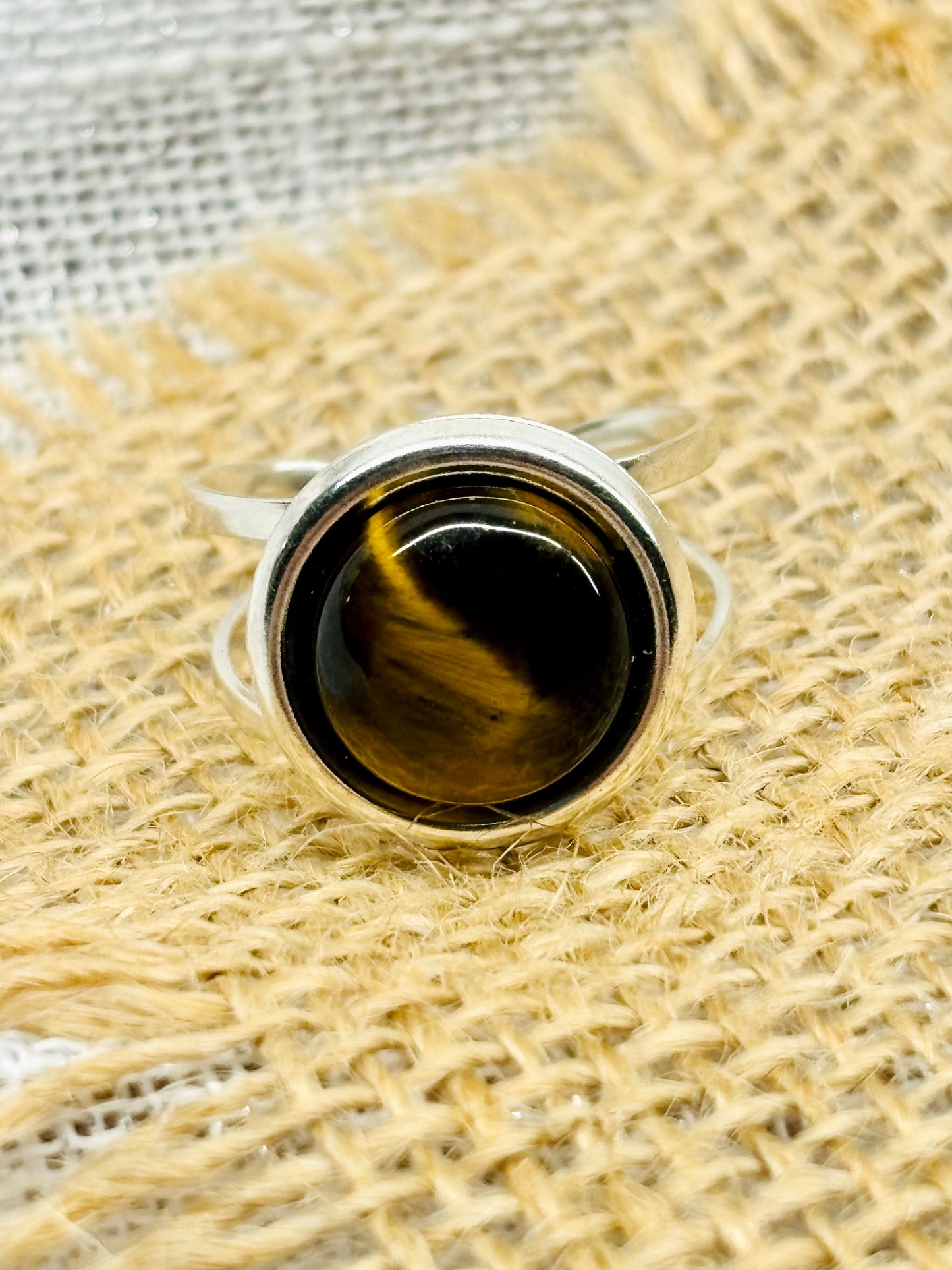 Bague THÉA, en argent et pierre d'Oeil de Tigre, sur un fond de toile de jute et lin.