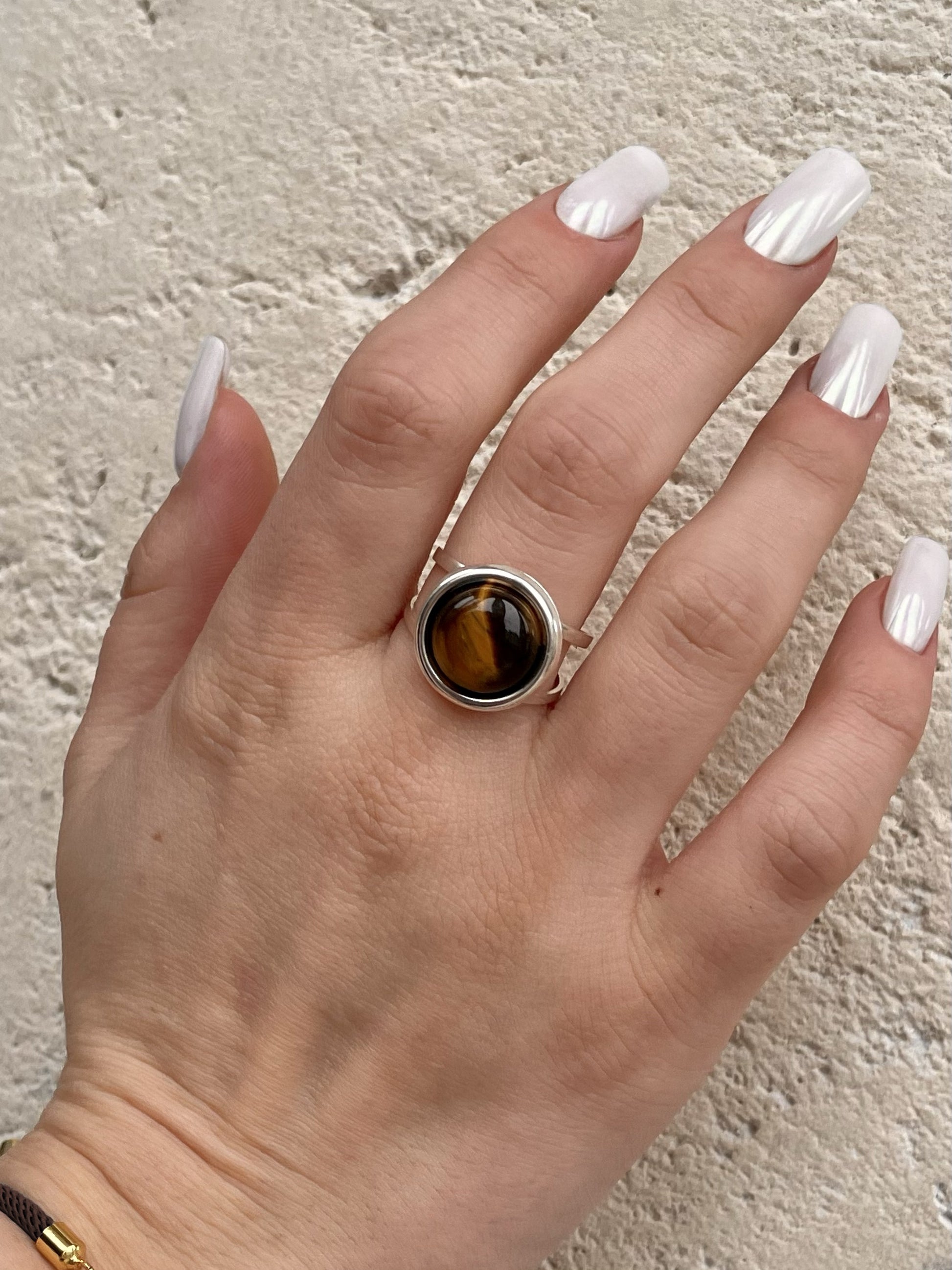 Bague THÉA, en argent et pierre d'Oeil de Tigre, portée sur une main de femme.