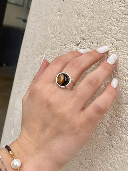 Bague THÉA, en argent et pierre d'Oeil de Tigre, portée sur une main de femme.