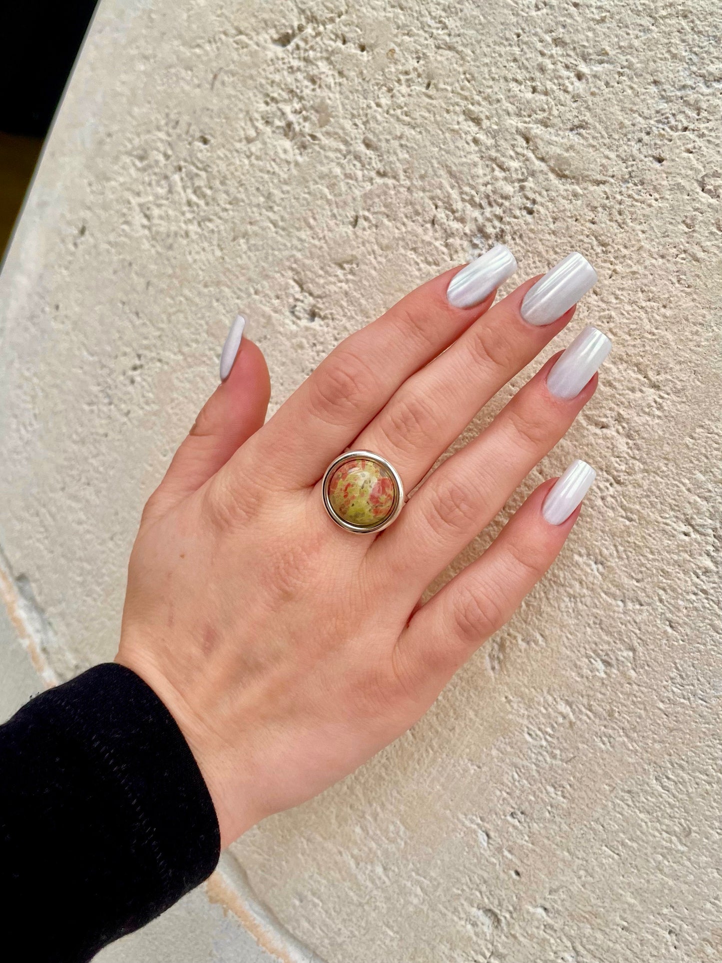 Bague THÉA, en argent et pierre d'Unakite, portée sur une main de femme.