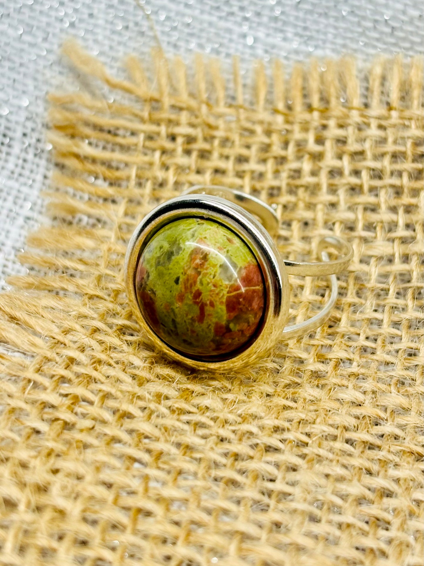 Bague THÉA, en argent et pierre d'Unakite, sur un fond en lin et toile de jute.