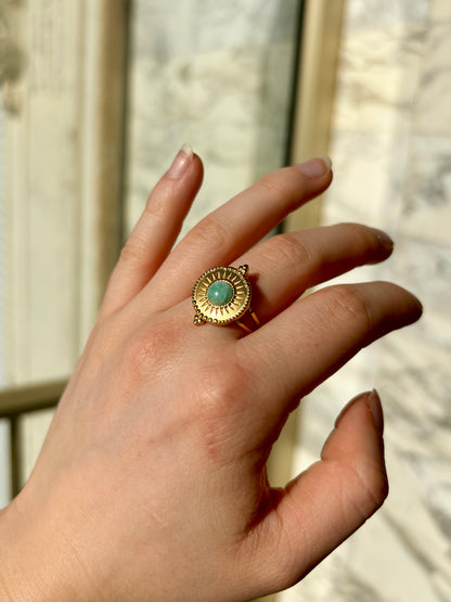 Bague ZÉLIE, en acier inoxydable doré et pierre d'amazonite, portée sur une main de femme.