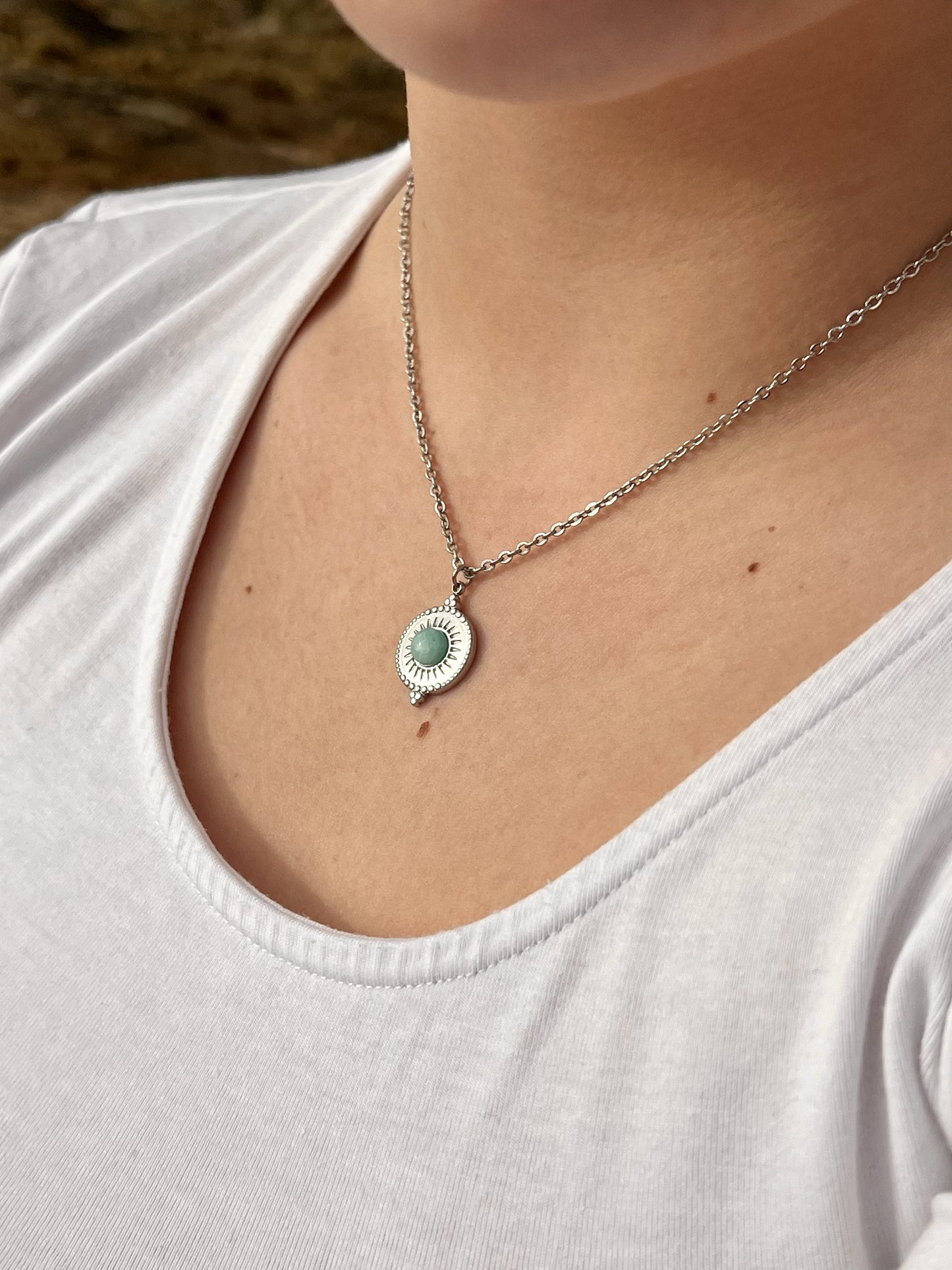 Collier ZÉLIE en acier inoxydable argent, avec pierre d'Amazonite, porté par une femme dans les rochers..